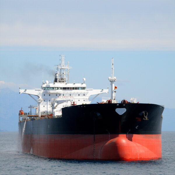 A large oil tanker, painted in red and black, approaches the viewer head-on while sailing through calm waters. Visible equipment and "NO SMOKING" signage on the superstructure highlight safety protocols. This type of vessel can utilize Fomtec’s firefighting foam systems to protect cargo and crew from fire hazards in high-risk maritime environments.